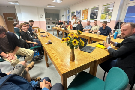 Mitglieder der BÜNDNIS 90 / DIE GRÜNEN sitzen um einen Tisch, rechts in der Ecke ist Clemens Rostock, Landesvorstand Brandenburg, zu sehen, auf dem Tisch steht eine Vase mit Sonnenblumen dem Logo der Grünen