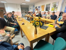 Mitglieder der BÜNDNIS 90 / DIE GRÜNEN sitzen um einen Tisch, rechts in der Ecke ist Clemens Rostock, Landesvorstand Brandenburg, zu sehen, auf dem Tisch steht eine Vase mit Sonnenblumen dem Logo der Grünen